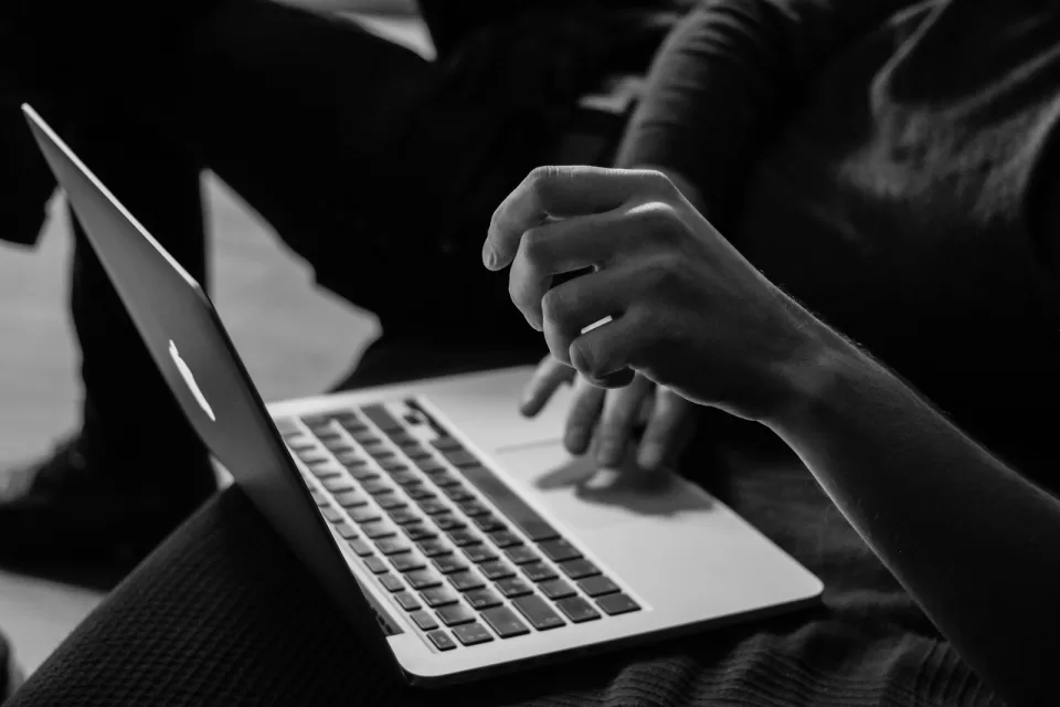 Hands typing on a laptop keyboard in black and white