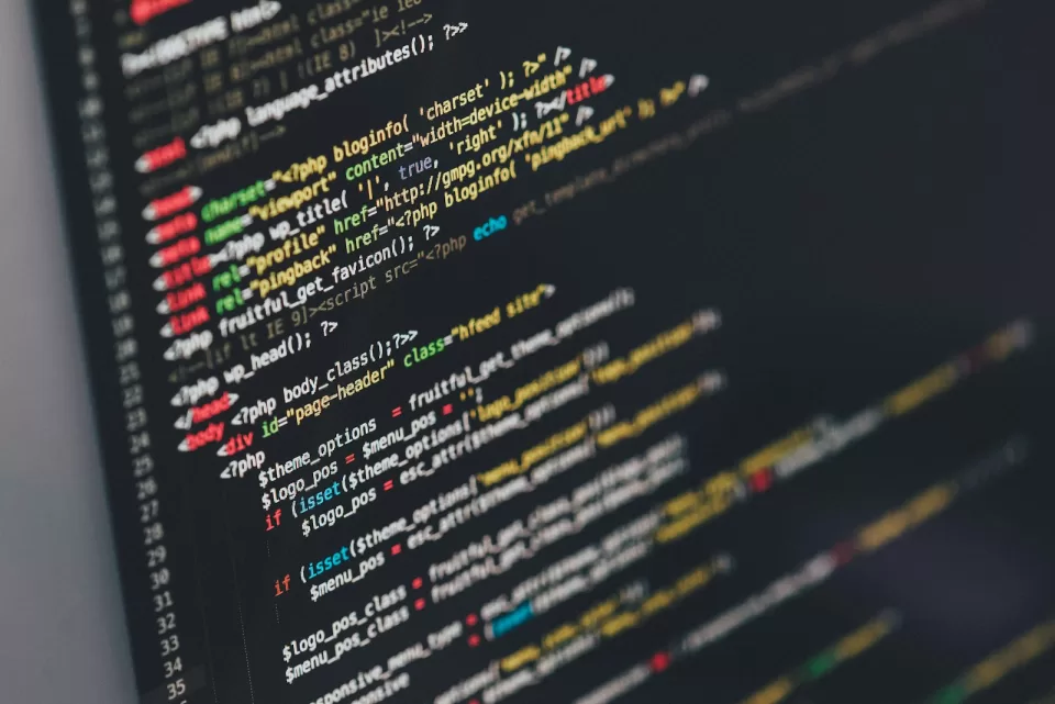 Close-up of colourful source code on a dark computer screen