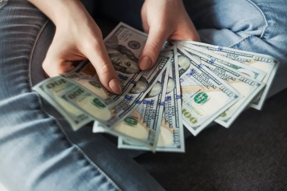 Person counting banknotes at a desk