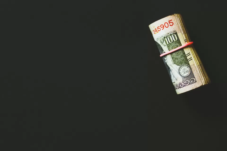 Rolled banknotes held with a rubber band on a dark surface