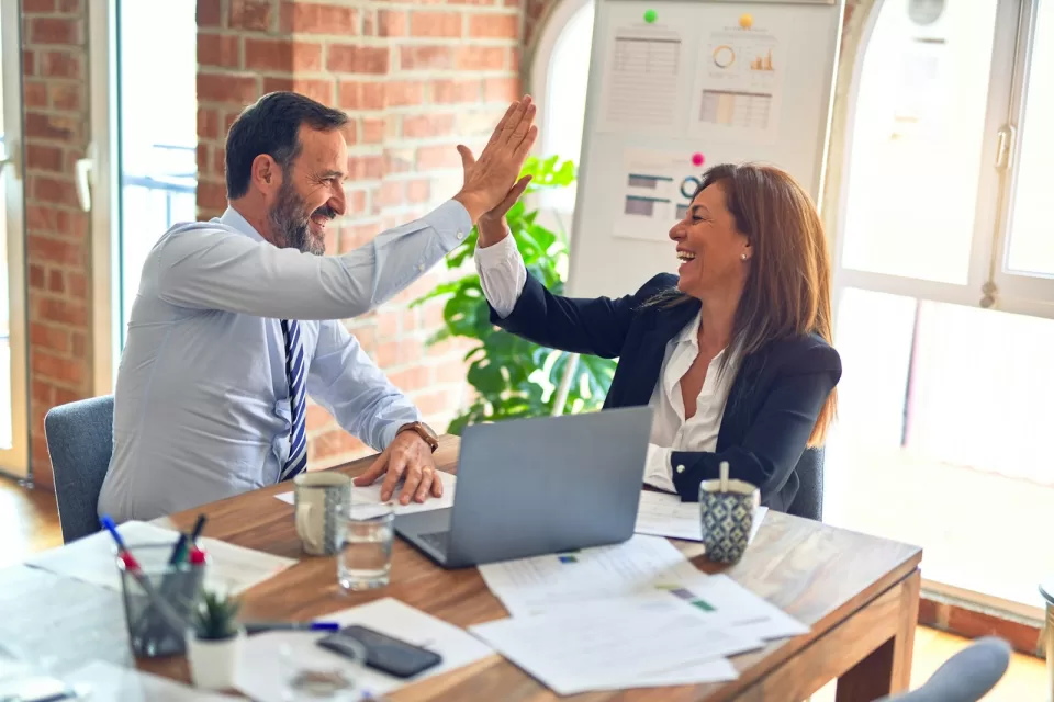 Two colleagues giving each other a high five in an office