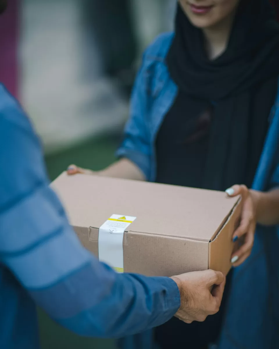 Person handing a sealed cardboard parcel to another person