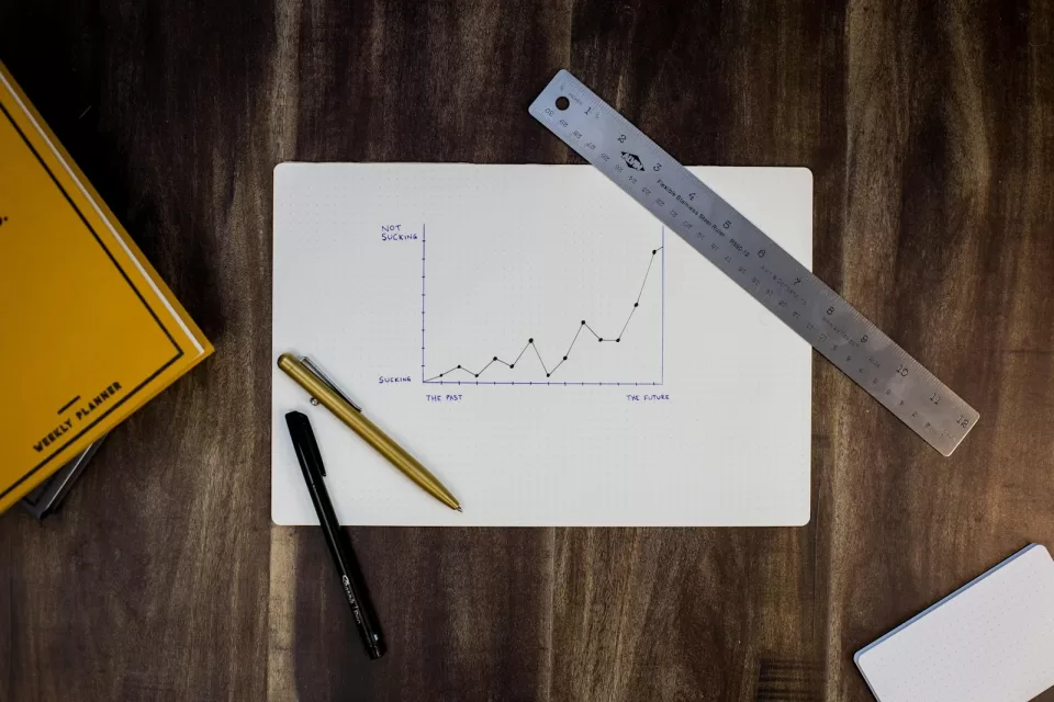 Printed charts and graphs on a desk beside a pen