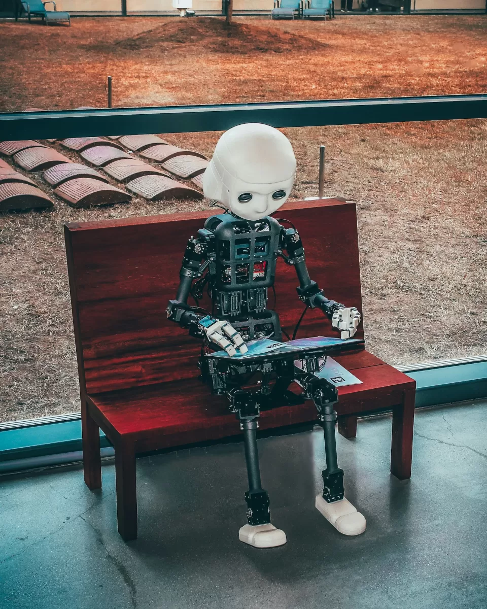 Small white robot holding a tablet as if reading it