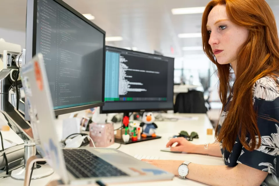 Developer working at a computer with code on two screens