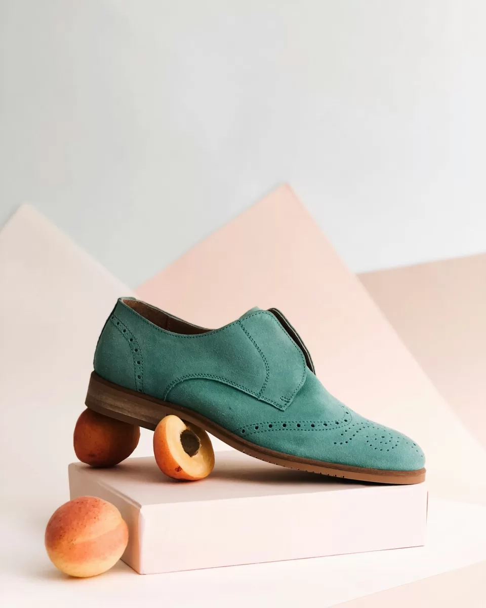 Single green trainer photographed on a plain background