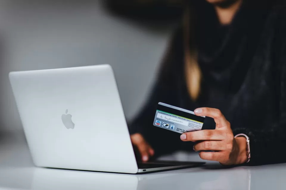 Person paying online with a bank card in front of a laptop