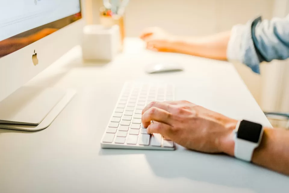 Person typing on a laptop, wearing a wristwatch
