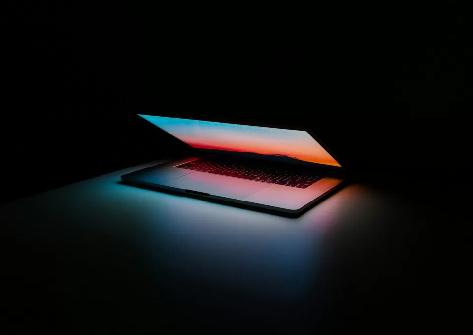 Laptop screen glowing with code in a dark room