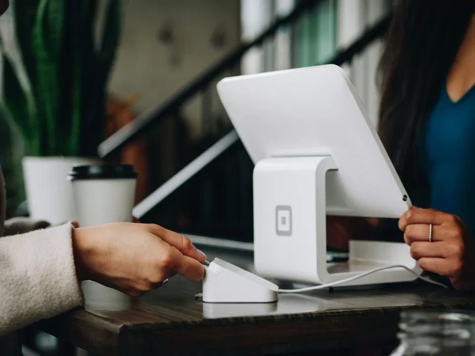 Customer handing a bank card to a shop assistant at a payment counter
