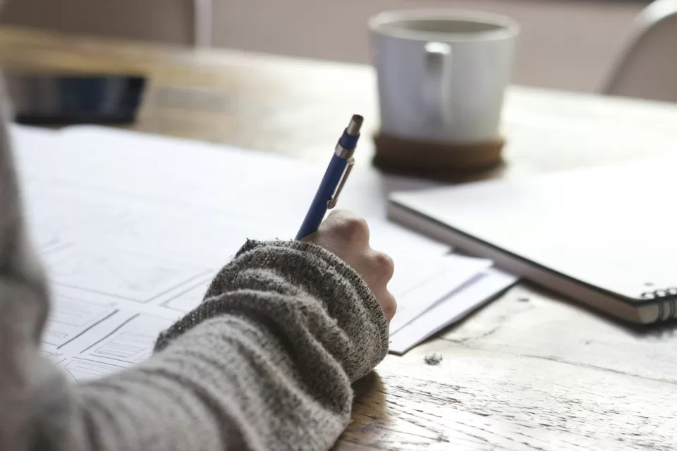 Person writing notes by hand in a notebook at a desk