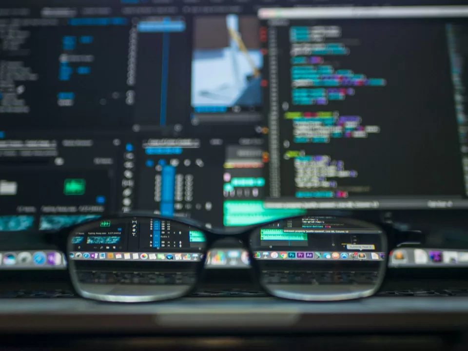 Glasses resting in front of computer monitors showing code