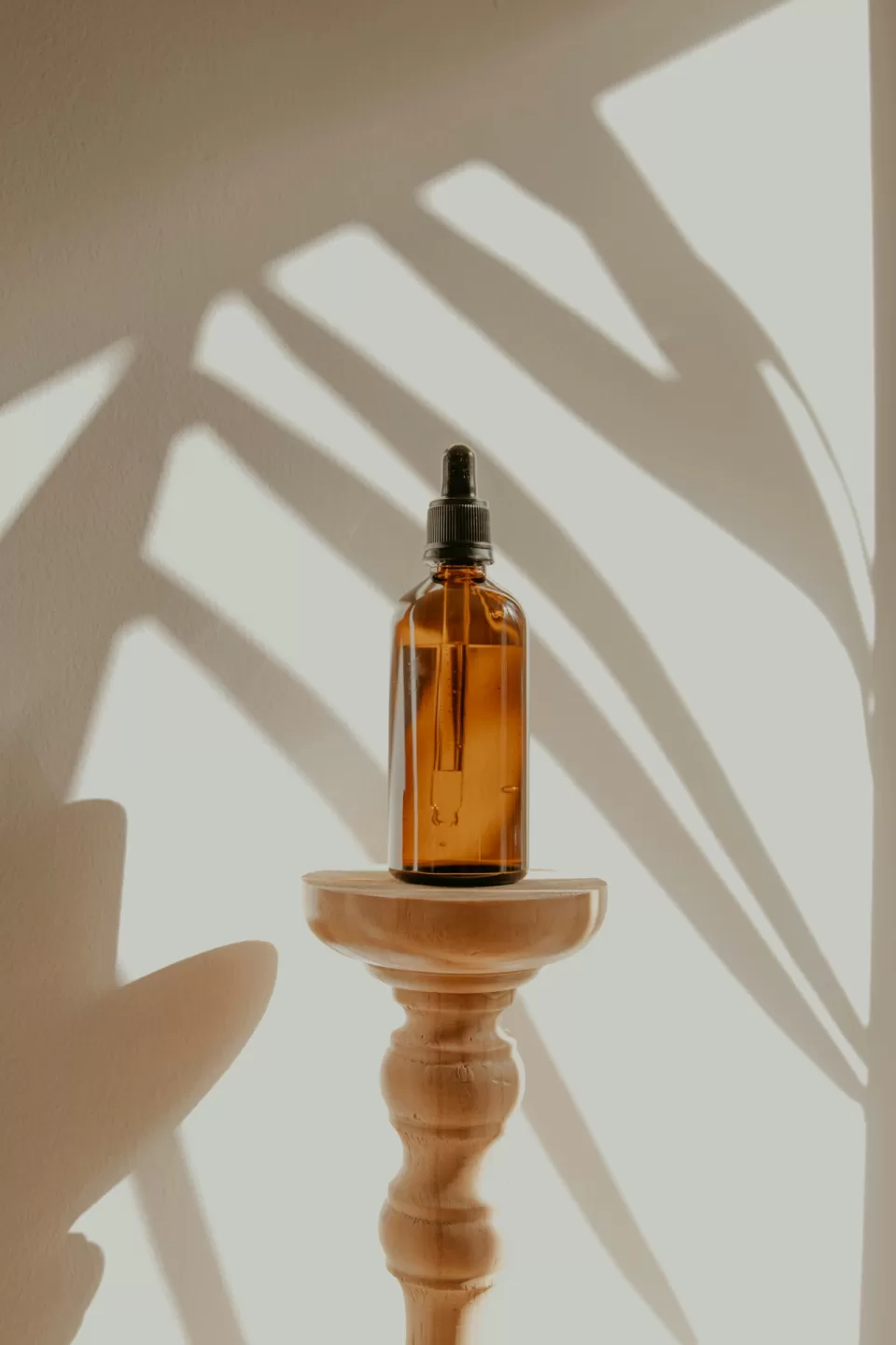Glass serum bottle with a dropper on a plain background