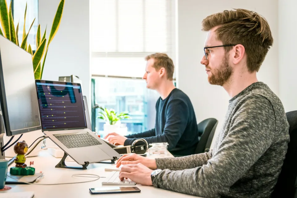 Two developers working side by side at their desks