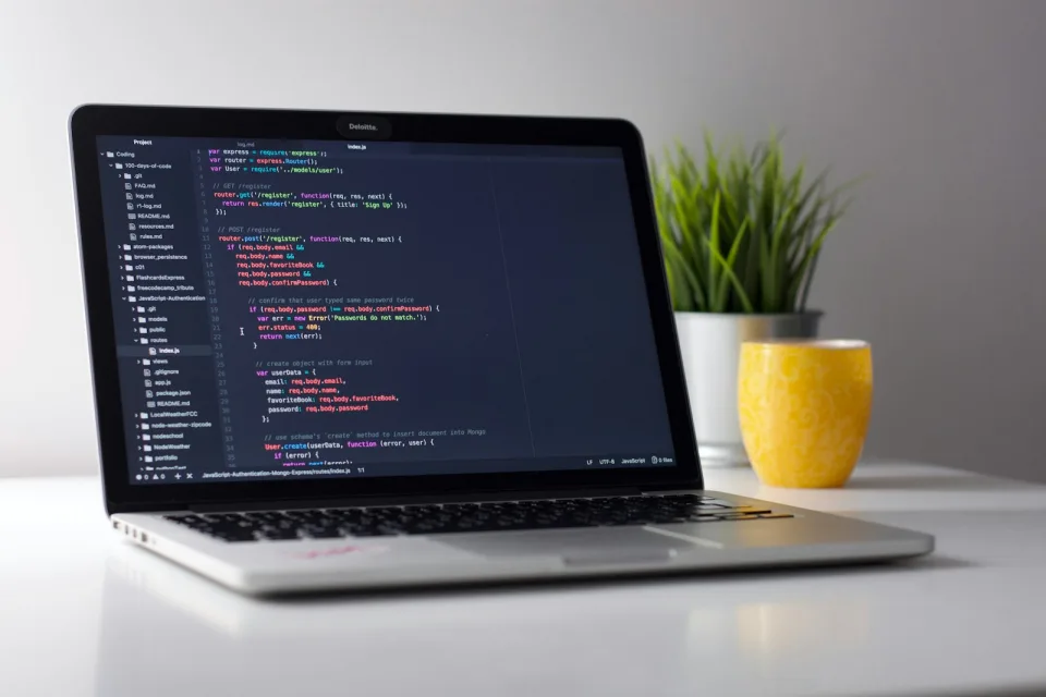 Laptop with front-end code next to a yellow mug